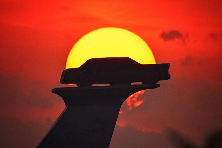 长春市汽车广场内的汽车雕塑沐浴在晨曦中。 新华社记者 许畅 摄