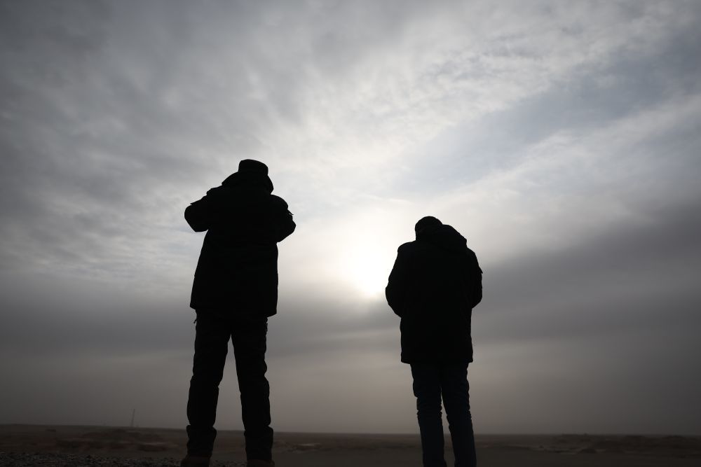 甘肃敦煌西湖国家级自然保护区管护中心玉门关保护站工作人员孙海隆（左）和同事肖永刚在保护区内用望远镜查看普氏野马活动情况（2月5日摄）