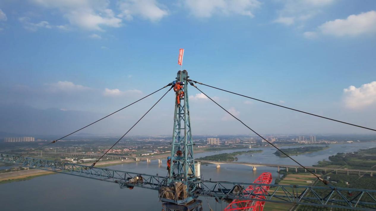 图为：佛山220千伏永丰站扩建工程北江大跨越段立塔、架线施工现场。