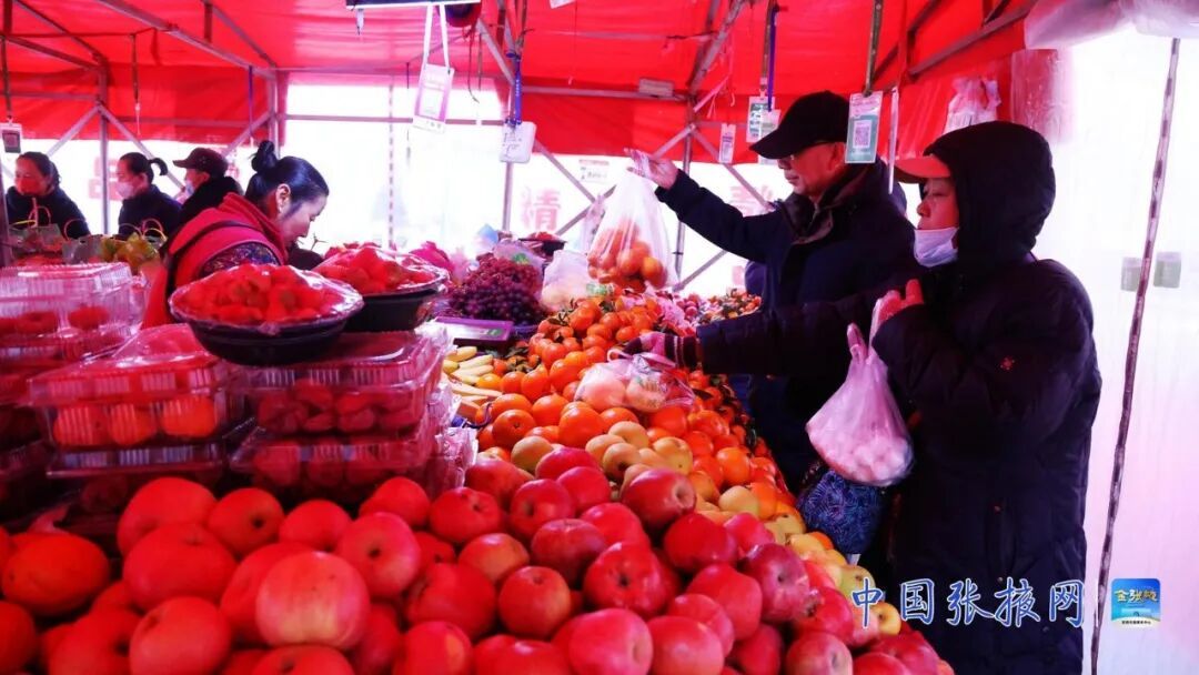 民乐县顺化镇居民在年货集市购买水果等年货