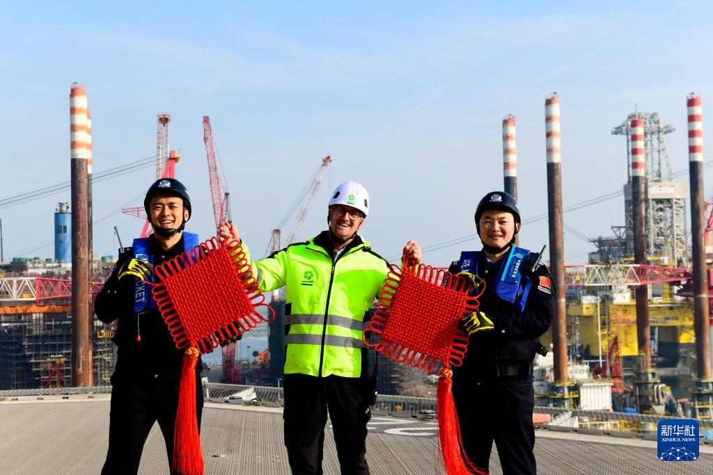 2月3日，在中集来福士山东烟台建造基地，山东出入境边防检查总站烟台边检站来福士警务室的民警赠送比利时风电安装船船长中国结，并合影留念。新华社记者 郭绪雷 摄