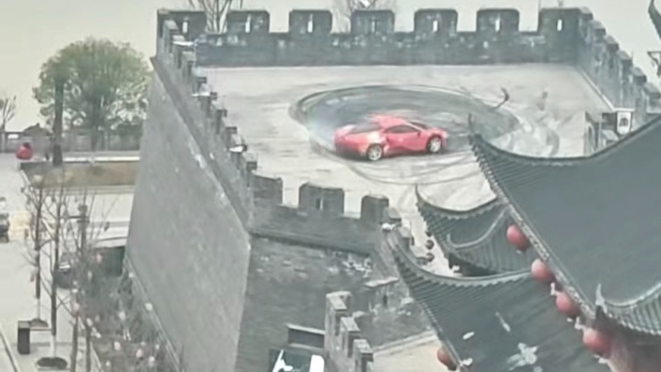 红色跑车在城墙上原地漂移转圈，当地：在拍宣传片