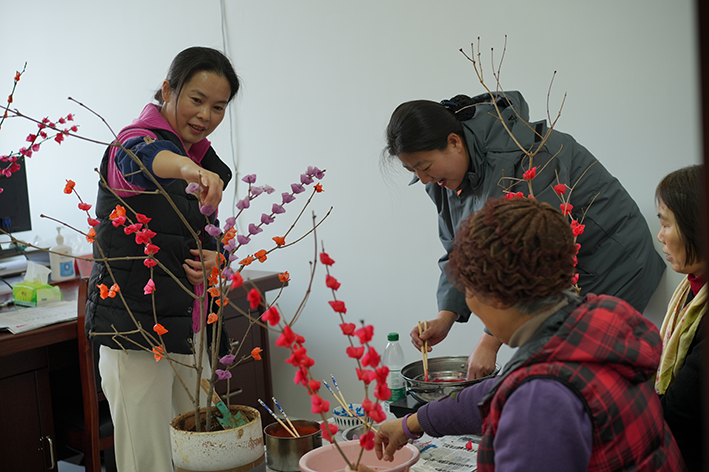 图为活动现场新裕路社区志愿者与居民制作腊梅花（朱李男摄）