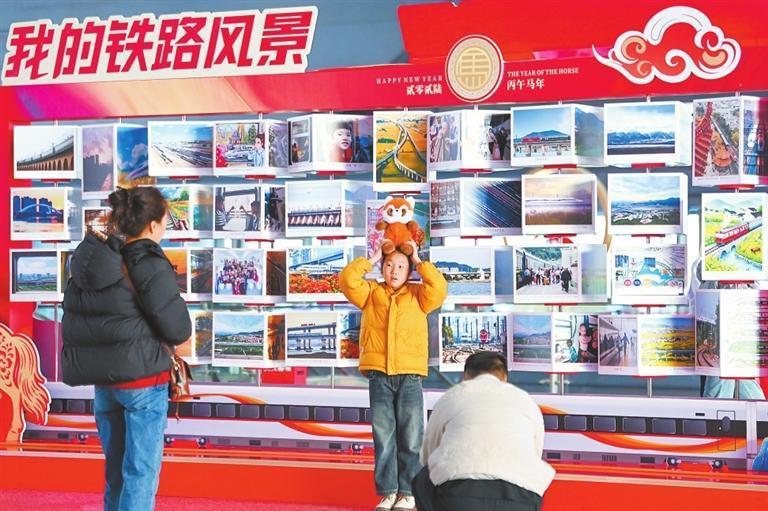 “我的铁路风景”摄影展前，一个小女孩举起玩偶，在镜头前留下可爱瞬间。