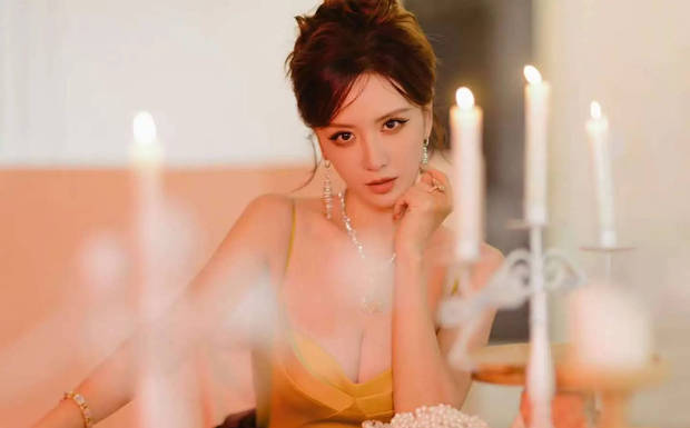 张萌托腮浅笑，烛光下神态温婉动人。