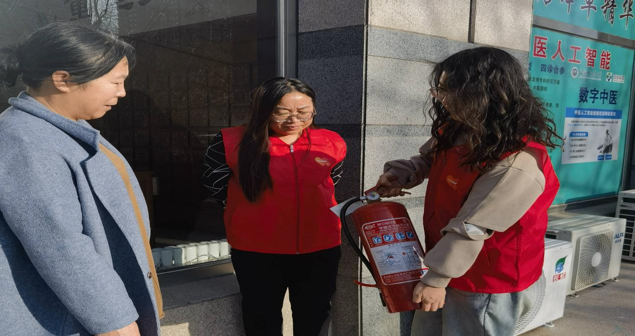 图片：平安志愿者演示灭火器使用方法