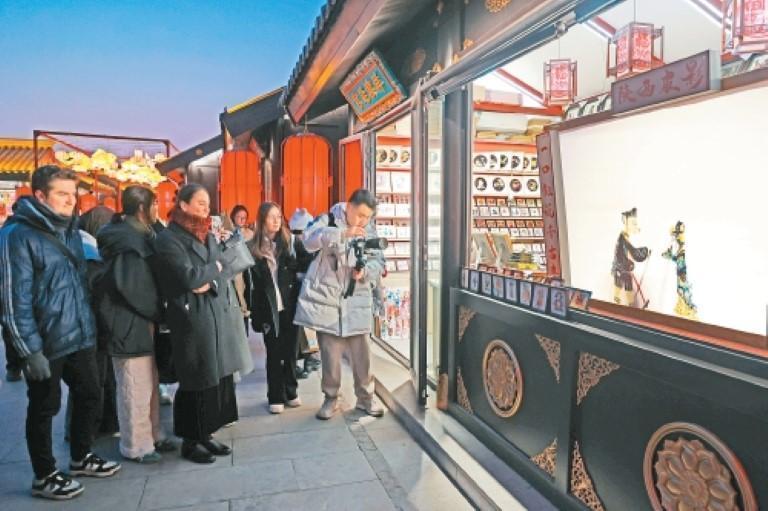 外籍友人被非遗皮影戏表演深深吸引。(记者 谢伟 摄)