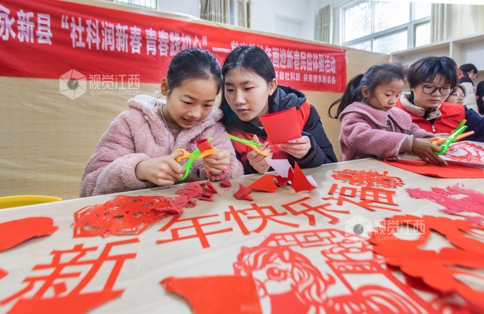 大学生志愿者在教孩子们剪窗花。