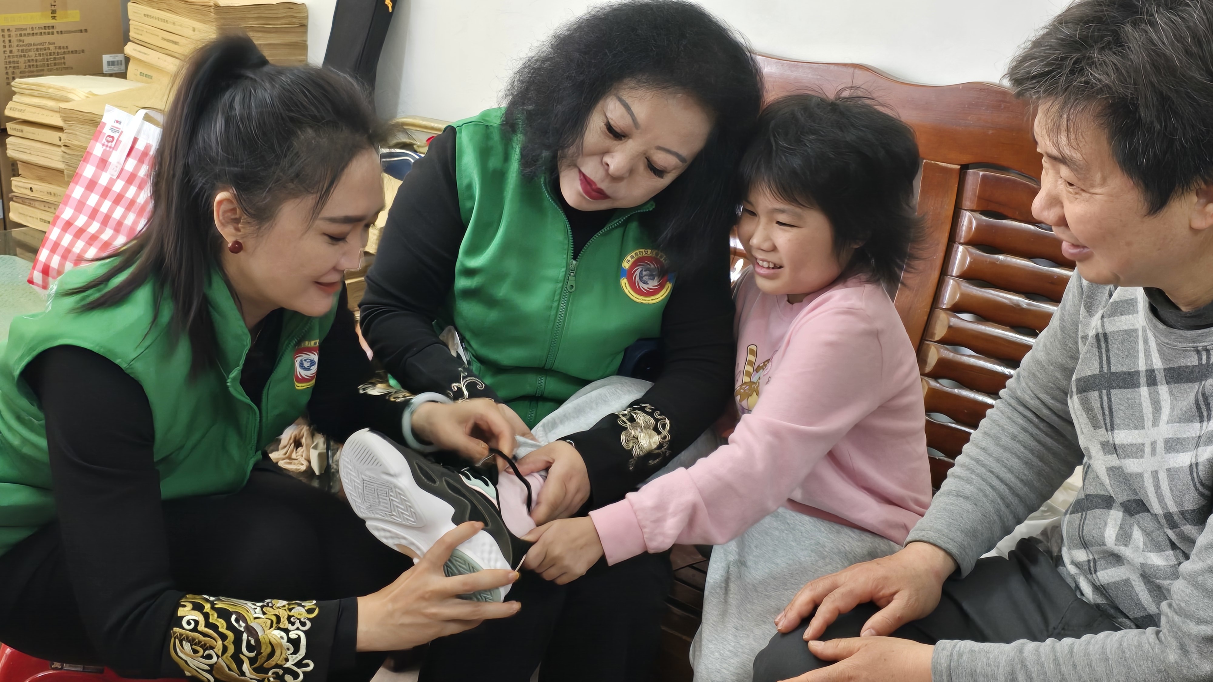 图为陈伟光及福利会工作人员为小星星试穿新鞋子