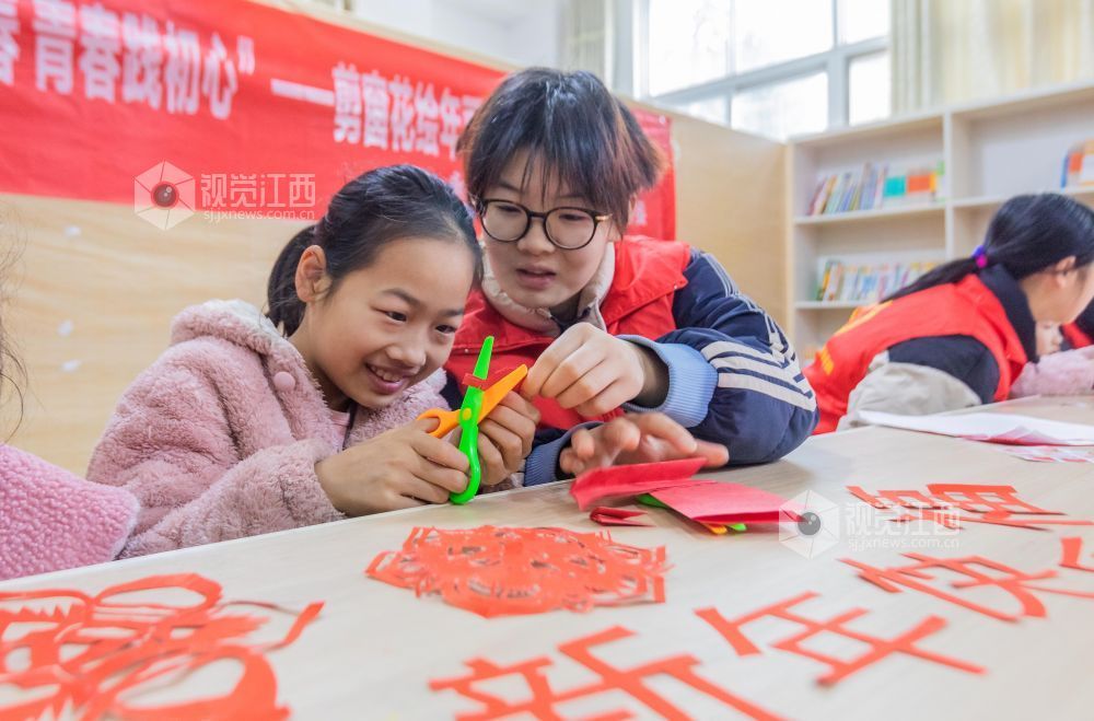 大学生志愿者在教孩子们剪窗花。