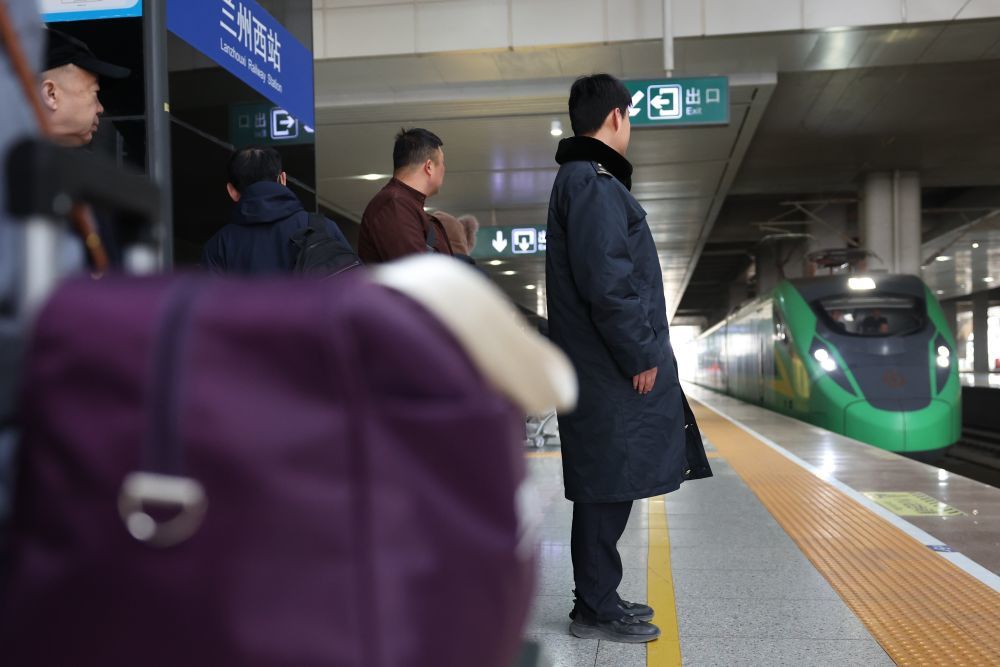 2月8日，中铁快运兰州西站营业部工作人员雒鹏（右）在站台上等待接收预约“轻装行”服务旅客的行李。新华社记者　陈斌　摄