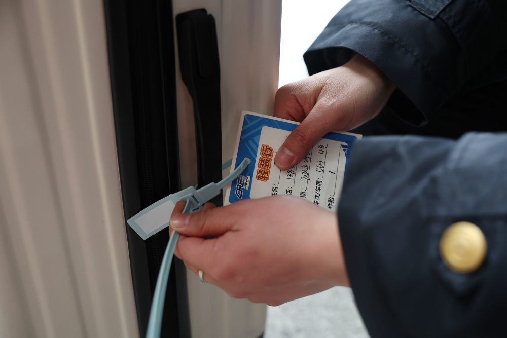 2月8日，中铁快运兰州西站营业部工作人员雒鹏将“轻装行”服务卡挂在旅客的行李上。新华社记者　陈斌　摄