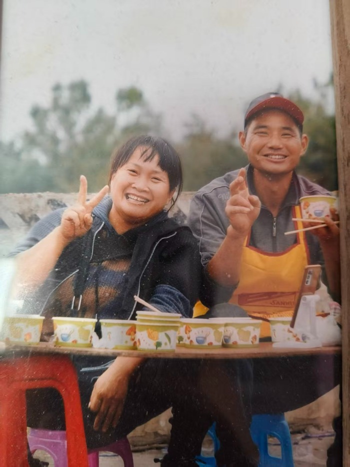 王荣亚和丈夫坐着一起吃盒饭。