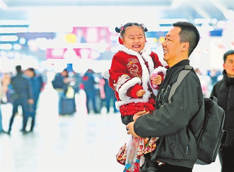 2026年2月2日，在郑州东站，身着新衣的小朋友在父亲怀中等待乘车，回家路上，涌动着中国人对团圆的温暖期盼。记者 王铮 摄