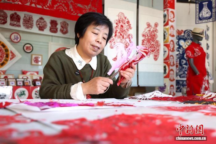 马年春节将至,甘肃省庆阳市西峰区,庆阳剪纸甘肃省级代表性传承人马路创作新春主题窗花。盘小美 摄