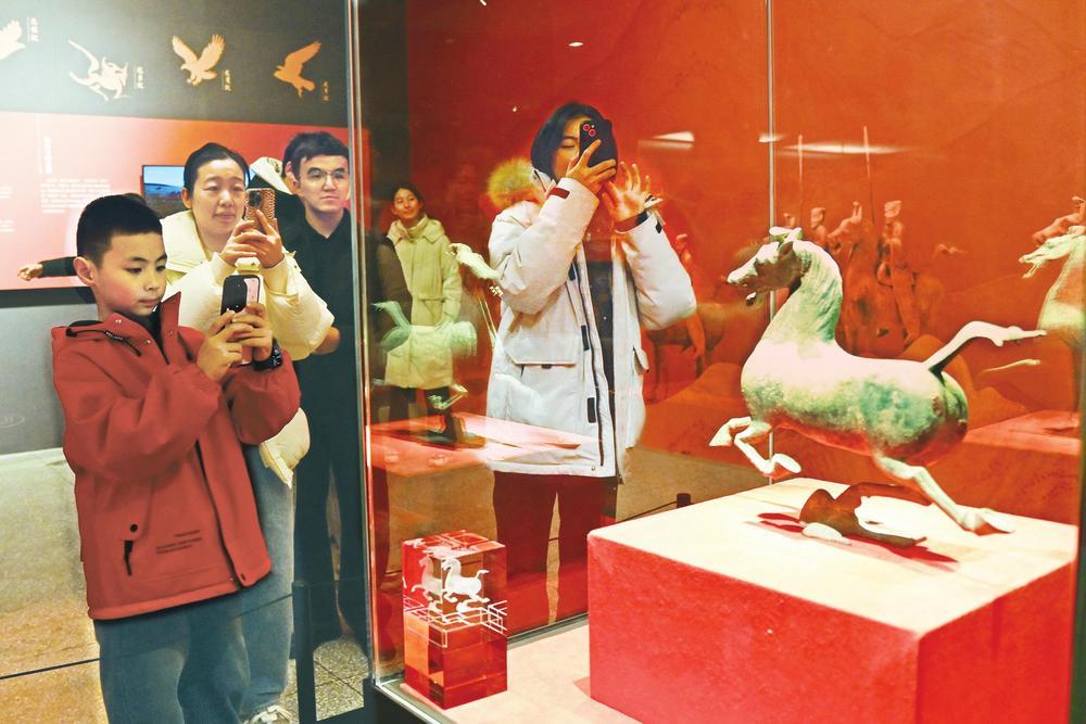 2月11日，游客在甘肃省博物馆观看铜奔马文物。近日，甘肃省博物馆推出“天驷——铜奔马特展”，本次展览精选30件馆藏文物。展览通过文物陈列、图文叙事与多媒体演绎，全面展现铜奔马的考古发掘历程、艺术价值与当代影响力。