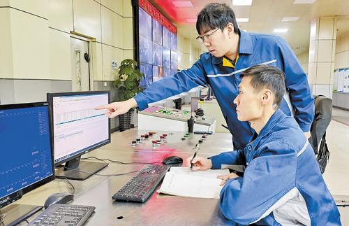 2月9日，唐笑宇（后）与同事一起查看生产计划。刘明婕摄