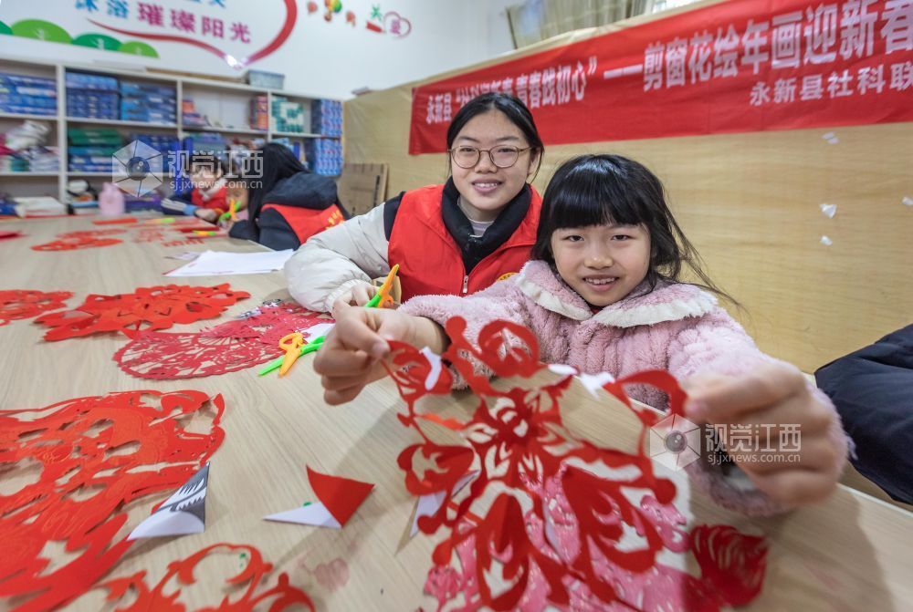 小孩子展示自己剪的窗花。