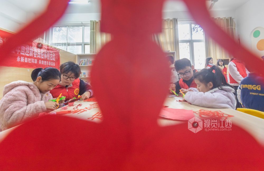 大学生志愿者在教孩子们剪窗花。