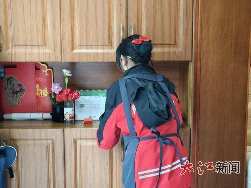 身着工装的家政员正专注整理橱柜。全媒体记者黄健恒摄