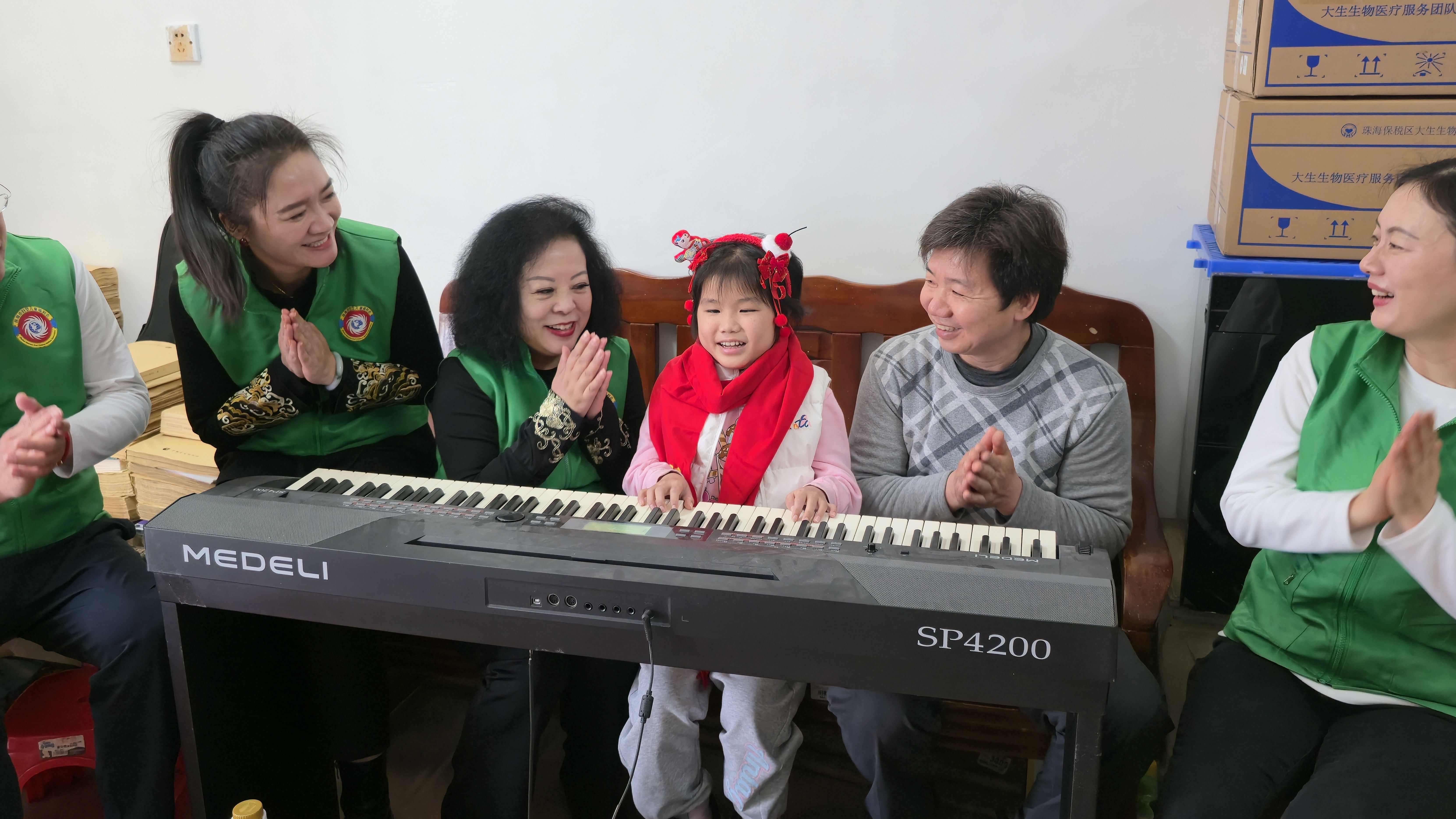 图为穿着新衣物的小星星现场弹奏,以琴声向陈伟光一行致谢