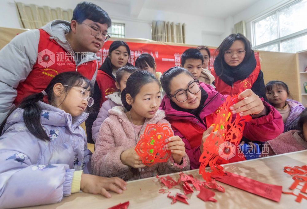 社科联志愿者在教孩子们剪窗花。