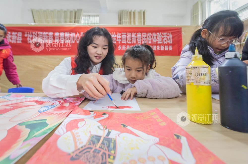 大学生志愿者在教孩子们绘年画。