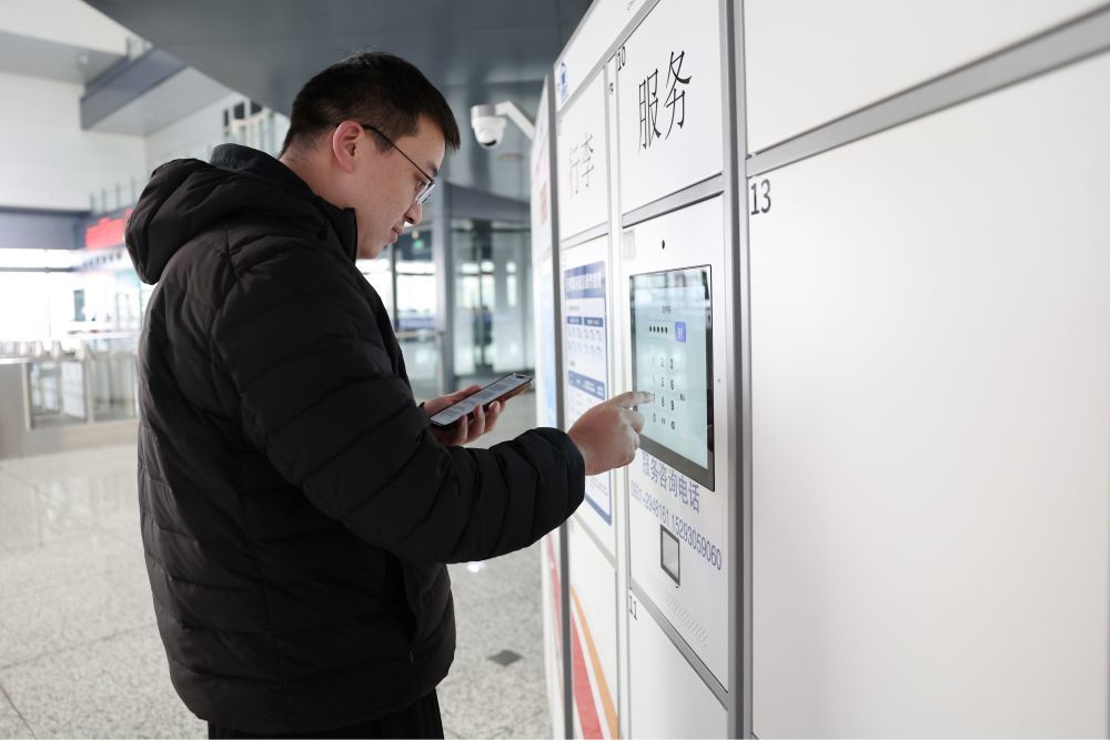 2月8日，准备搭乘高铁回家的旅客吴祥在兰州西站候车厅“轻装行”自助服务柜前输入取件码取出自己的行李。新华社记者　陈斌　摄