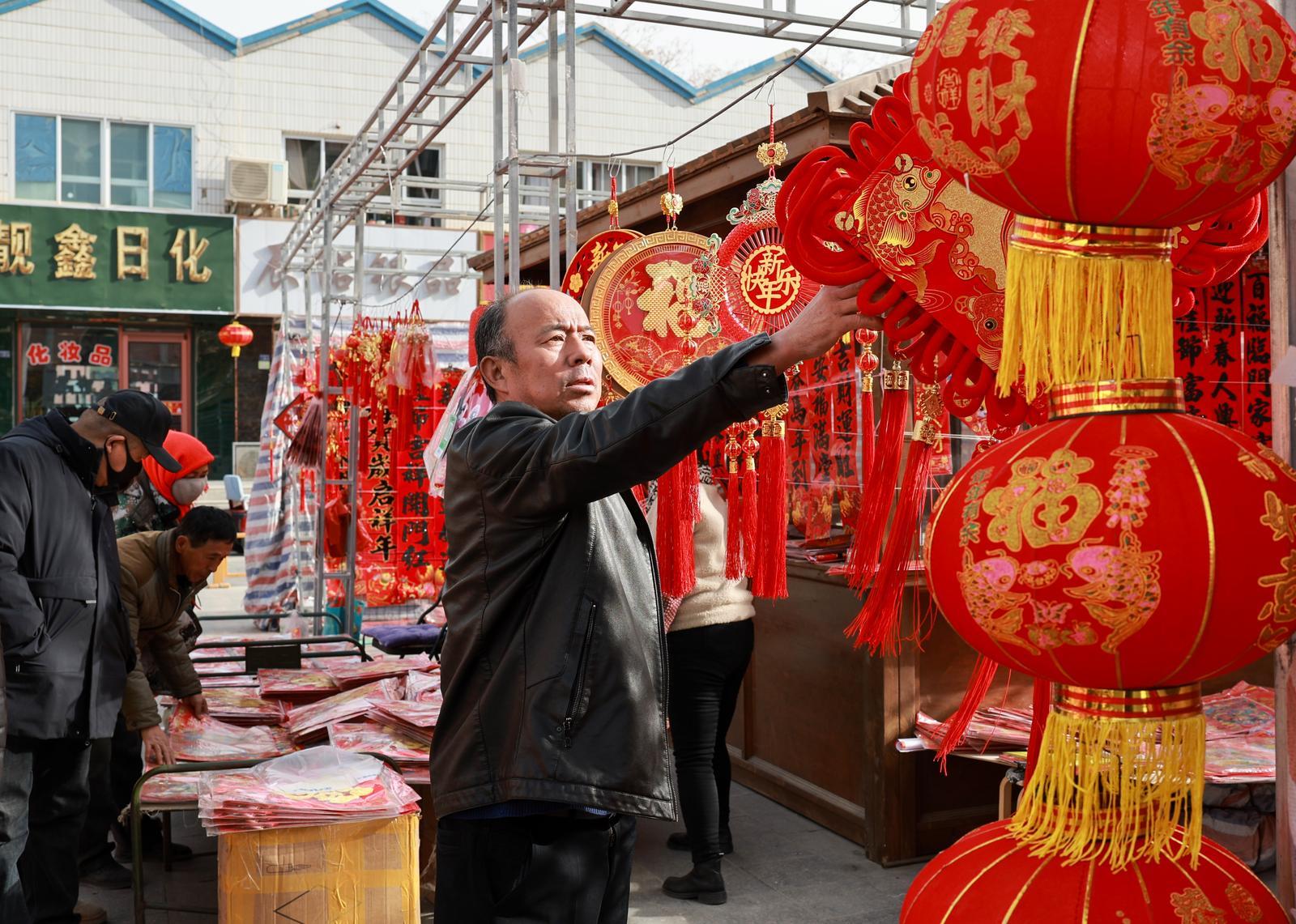 春节将至，金塔县年货市场销售红红火火，商家纷纷挂起红灯笼、春联、中国结等喜庆饰品，洋溢着浓浓的年味，吸引市民前来选购。