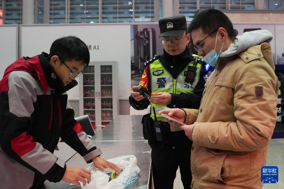2月9日，快递员和民警在长沙南站协助旅客（右）办理寄件。