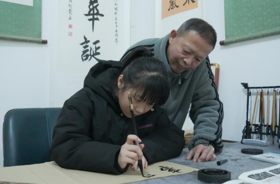 白杨镇武铜社区“一老一小”幸福院，李阿彭指导孙女梅曦练习毛笔字
