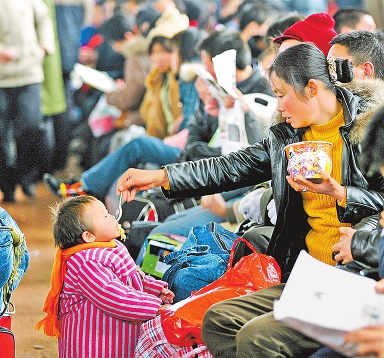 右图 2006年春运，在郑州火车站候车室内，等待乘车的母亲在给孩子喂食桶装方便面。记者 白周峰 摄