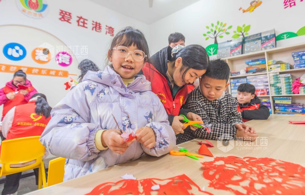 大学生志愿者在教孩子们剪窗花。