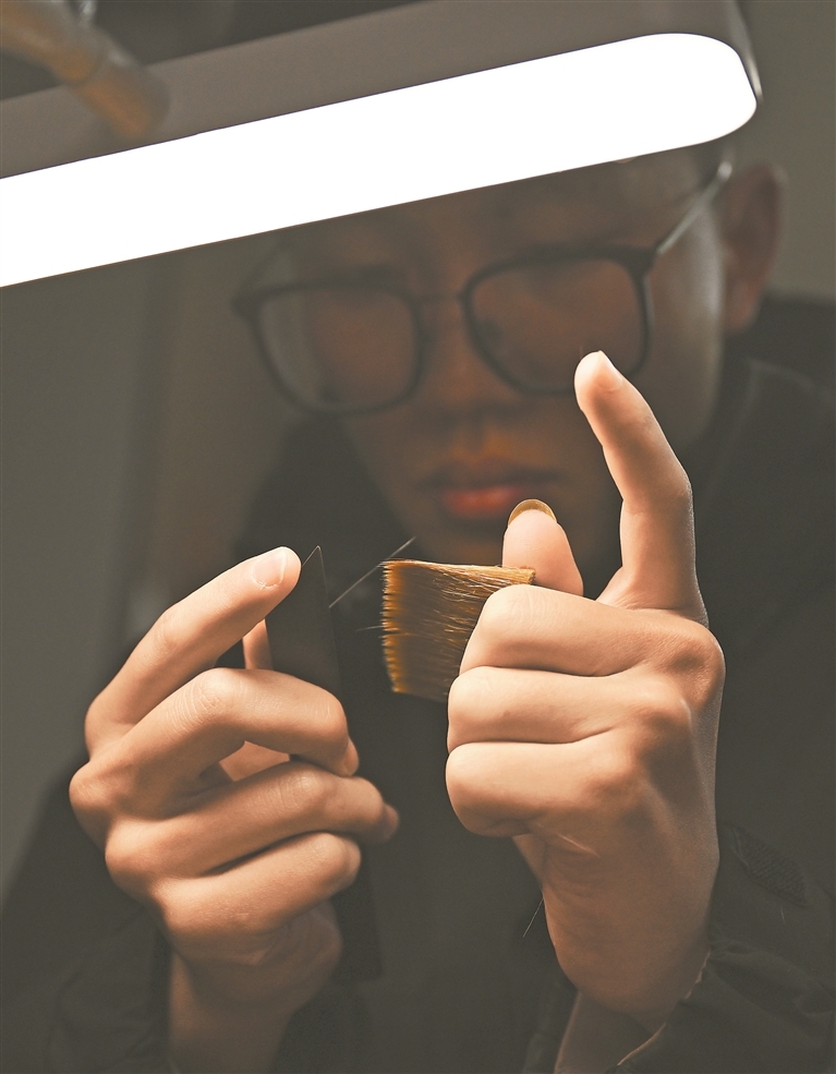 2月4日，在进贤县文港镇，年轻笔匠、“江西省技术能手”徐逸篪在灯光下用梳子反复梳洗毫料，去除杂毫。