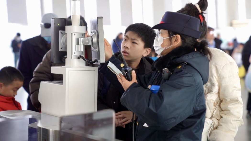 工作人员帮助旅客检票进站。