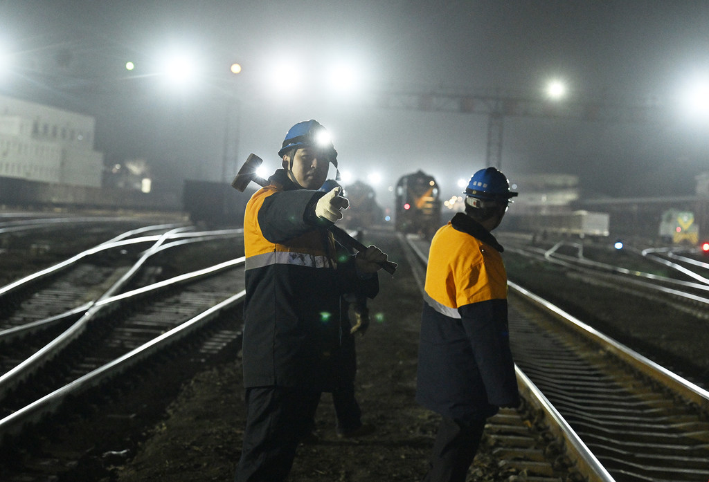 2月10日，孔明烨（左）和工友带着检测工具，穿过铁路编组站，走向作业区域。
