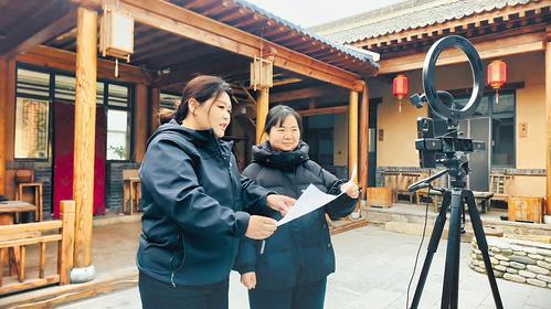 2月6日,在阜平县顾家台村民宿“听风院”内,刘娇(左)指导顾秋菊练习直播技巧。 本报记者 徐 华摄