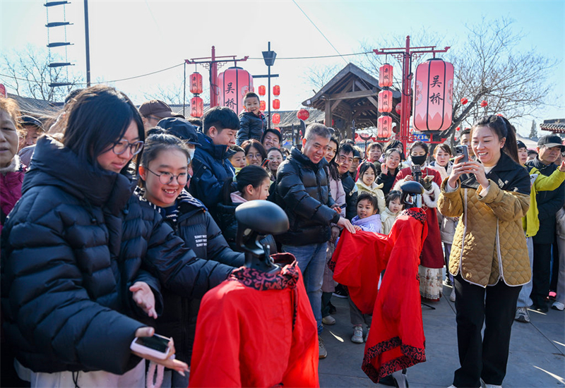 2月18日，游客在吴桥杂技大世界与表演杂技的机器人互动。
