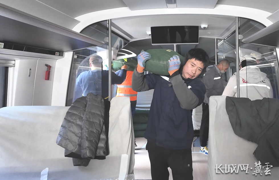 装卸工人张力和伙计们将一袋袋沙袋扛进崭新的京雄快线列车里。李征 摄