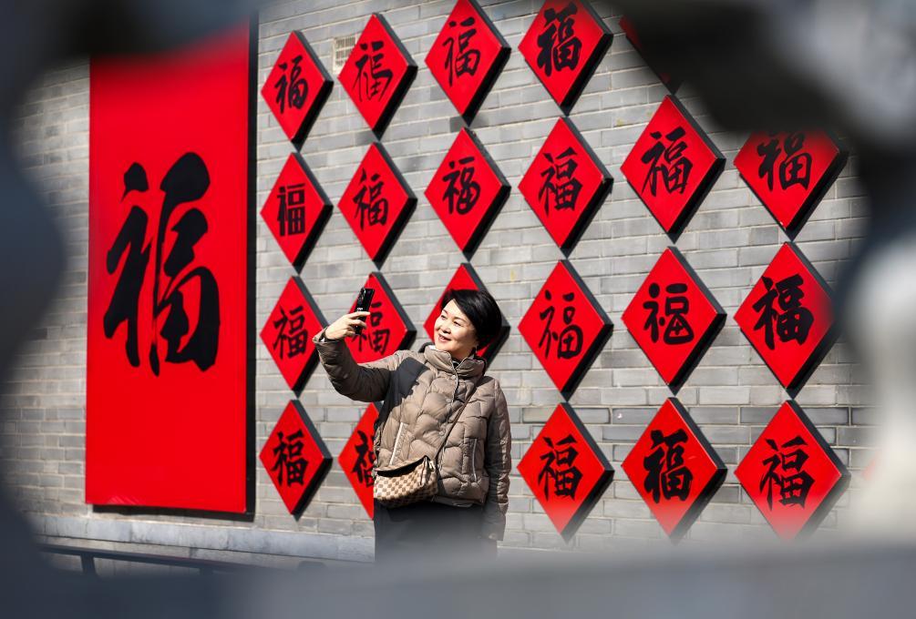 2月17日，在甘肃省兰州市七里河区老街，人们在福字墙下合影留念。新华社发（侯崇慧　摄）