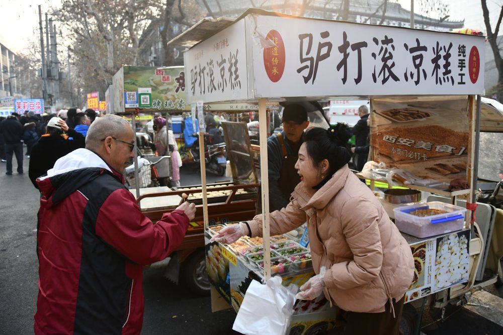 2月17日，张艳（右）在小南门早市邀请游客试吃手工制作的凉糕。 新华社记者 姚友明 摄