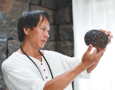 吴名驹正在认真打量他的椰雕作品（张丽芸摄/来源新华社）