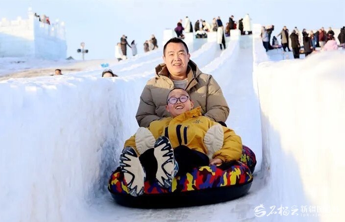阿勒泰冰雪主题乐园中,父子同玩雪滑梯。宋湖拉·沙布尔江摄