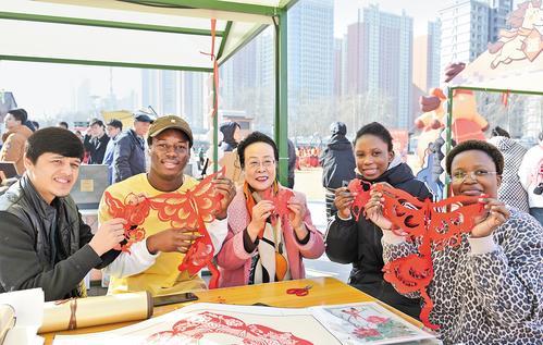 2月12日,在石家庄织音1953文化创意园区,河北中医药大学留学生们与周淑英(中)一起展示剪纸作品。 本报记者 刘冉摄