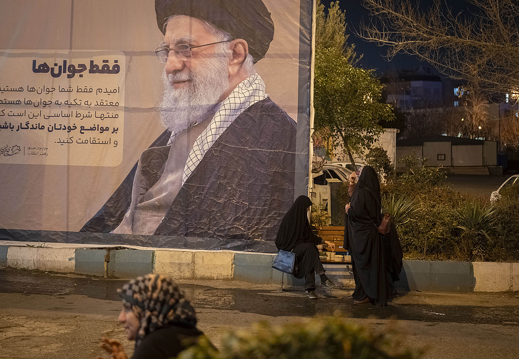 当地时间2026年2月20日，伊朗德黑兰，一个伊朗家庭在伊玛目霍梅尼大清真寺参加活动，在斋月第二天结束时坐在伊朗最高领袖阿亚图拉阿里·哈梅内伊的画像下开斋。