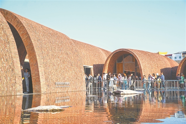 2月21日,在景德镇御窑博物馆前,拱形建筑与水面倒影相映成趣,打卡拍照的游客络绎不绝。本报全媒体记者 吴福清摄