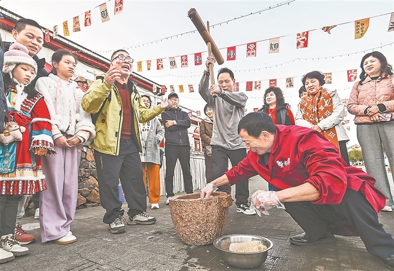 2月20日,来自广东的游客在资溪县乌石镇新月畲族村体验打糍粑。特约通讯员 吴志贵摄