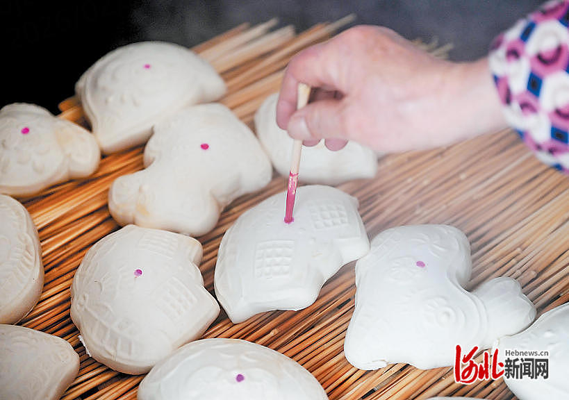 2月8日,张瑞霞为刚出锅的面花点红。