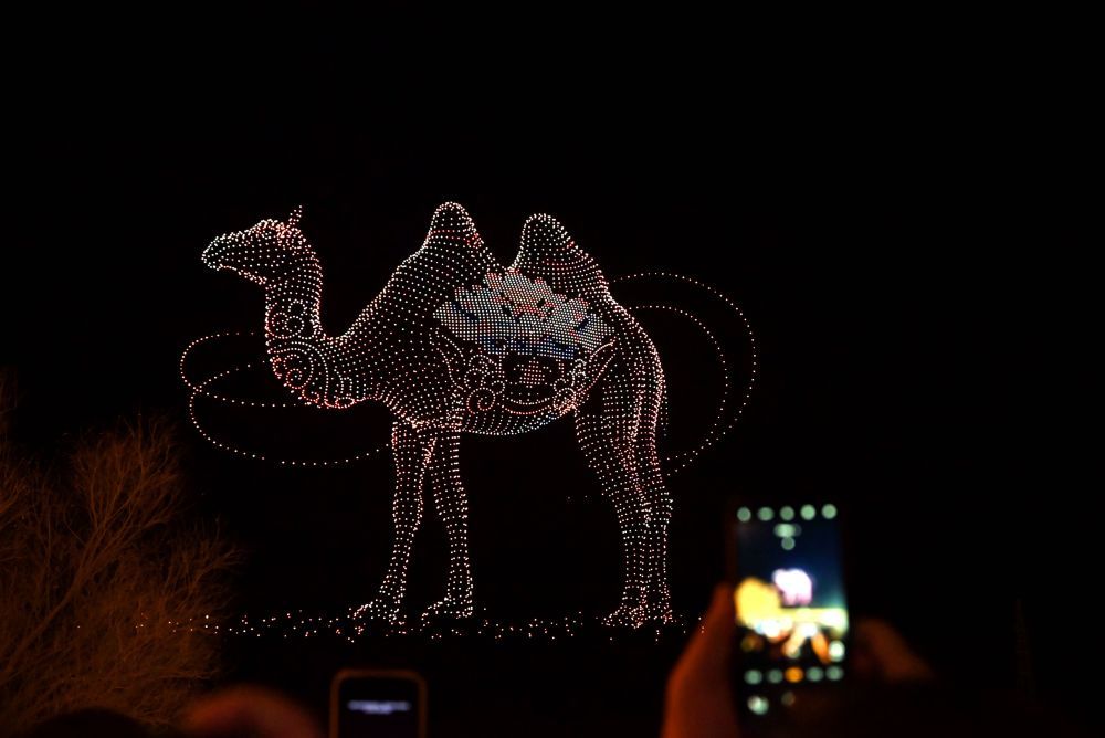 2月22日晚，人们在甘肃省敦煌市党河风情线观看无人机光影秀。新华社发（张晓亮　摄）