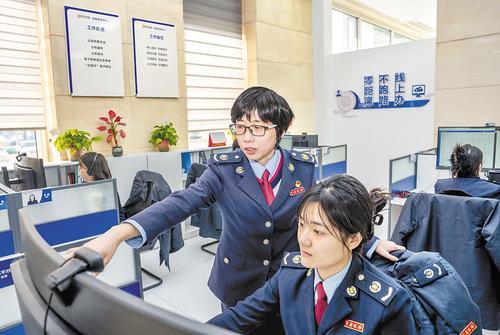 2月14日，孟庆茹（左）和同事一起在线上为纳税人解答问题。 本报记者 赵 杰摄